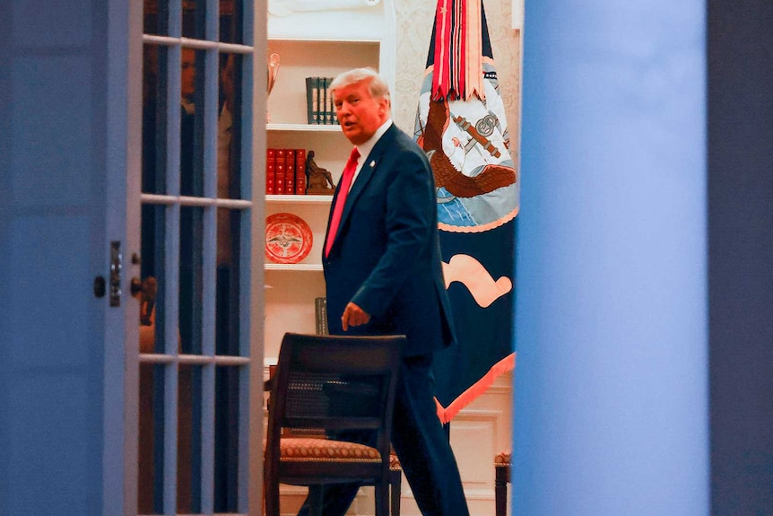 Donald Trump walking past an open door in the Oval Office