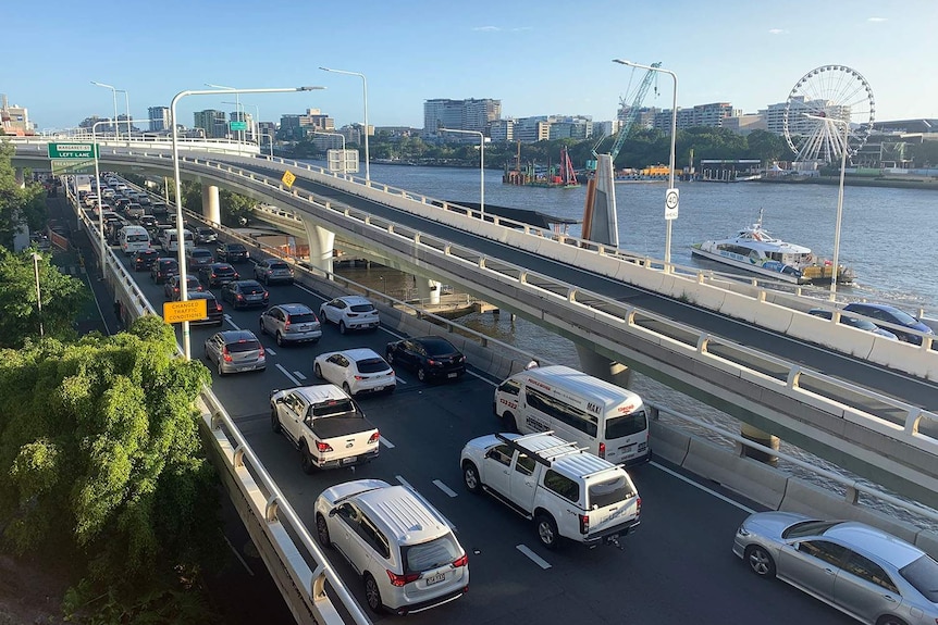Cars banked up on a highway next to the Brisbane River.