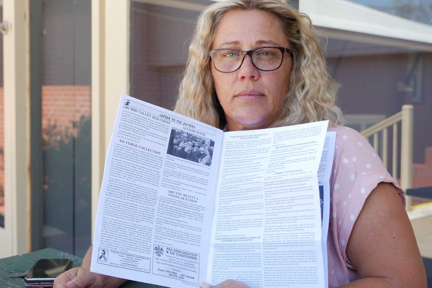 A photo of a woman holding a paper newsletter.