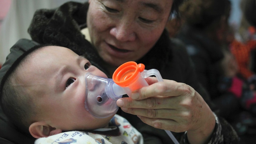 A baby with respiratory disease undergoes inhalation therapy with help of his grandmother.