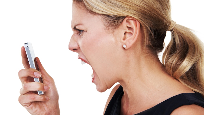 Side view of woman with blonde ponytail screaming into mobile phone in her hand