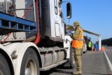Australian Defence Force personnel checks a driver's papers at a South Australian border checkpoint.