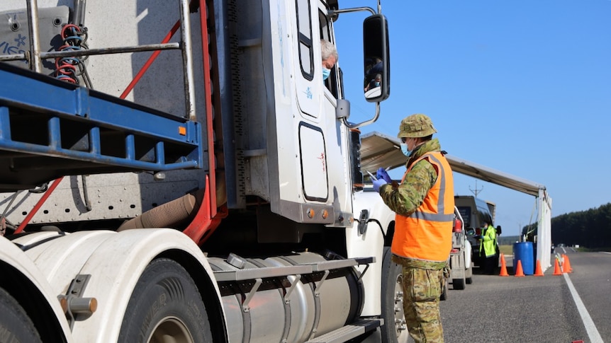 Australian Defence Force personnel checks a driver's papers at a South Australian border checkpoint.