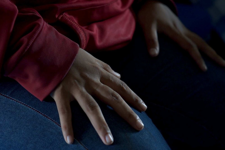 A woman's hands rest on her legs.