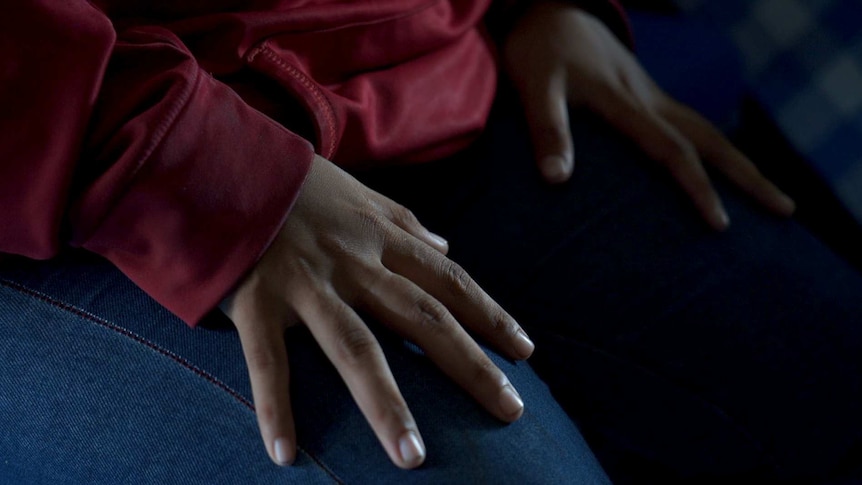 A woman's hands rest on her legs.