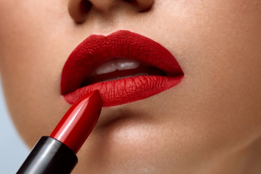close up of bright red lipstick being applied to lips