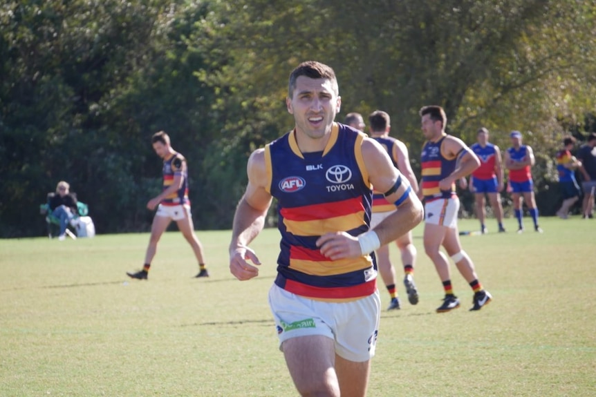 Stefan Barr, wearing an Adelaide Crows football uniform, runs towards the camera. 