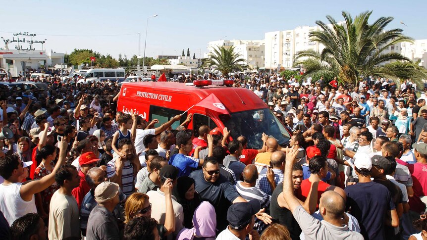 Tunisians walk beside the ambulance carrying the body of Mohamed Brahmi.