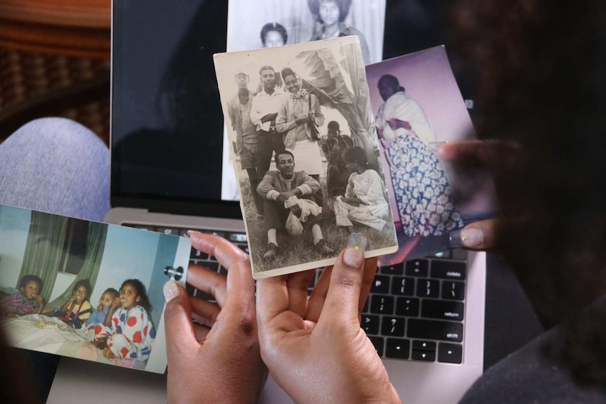 The hands of two people holding family photographs
