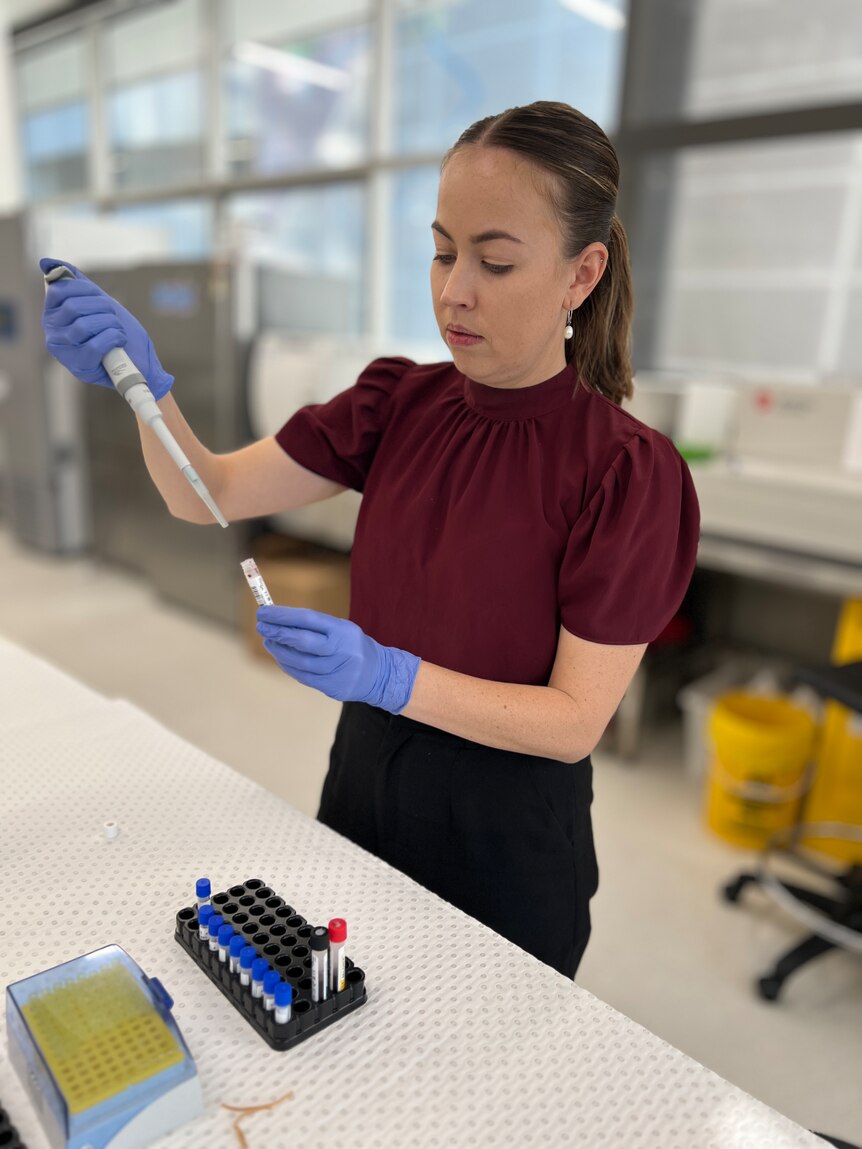 A woman wearing  blue latex gloves in a lab