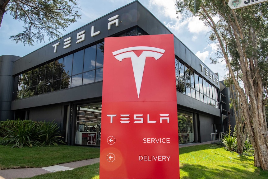 A Tesla sign in front of a Tesla building.