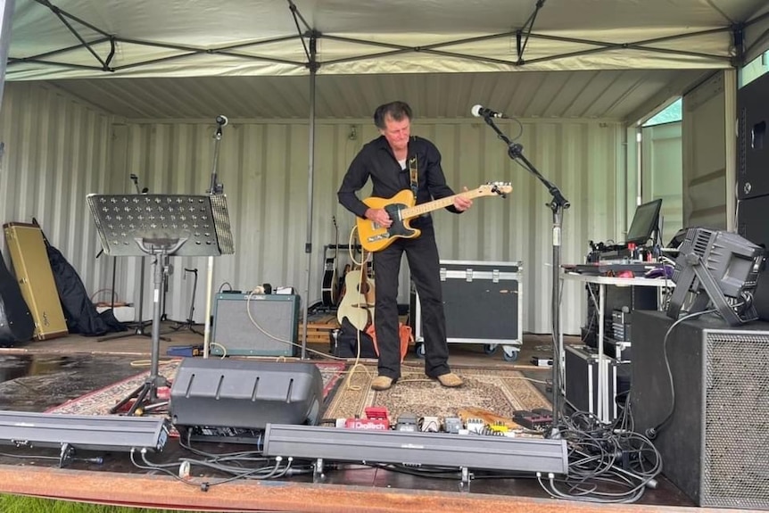 A man stands on stage playing a guitar.