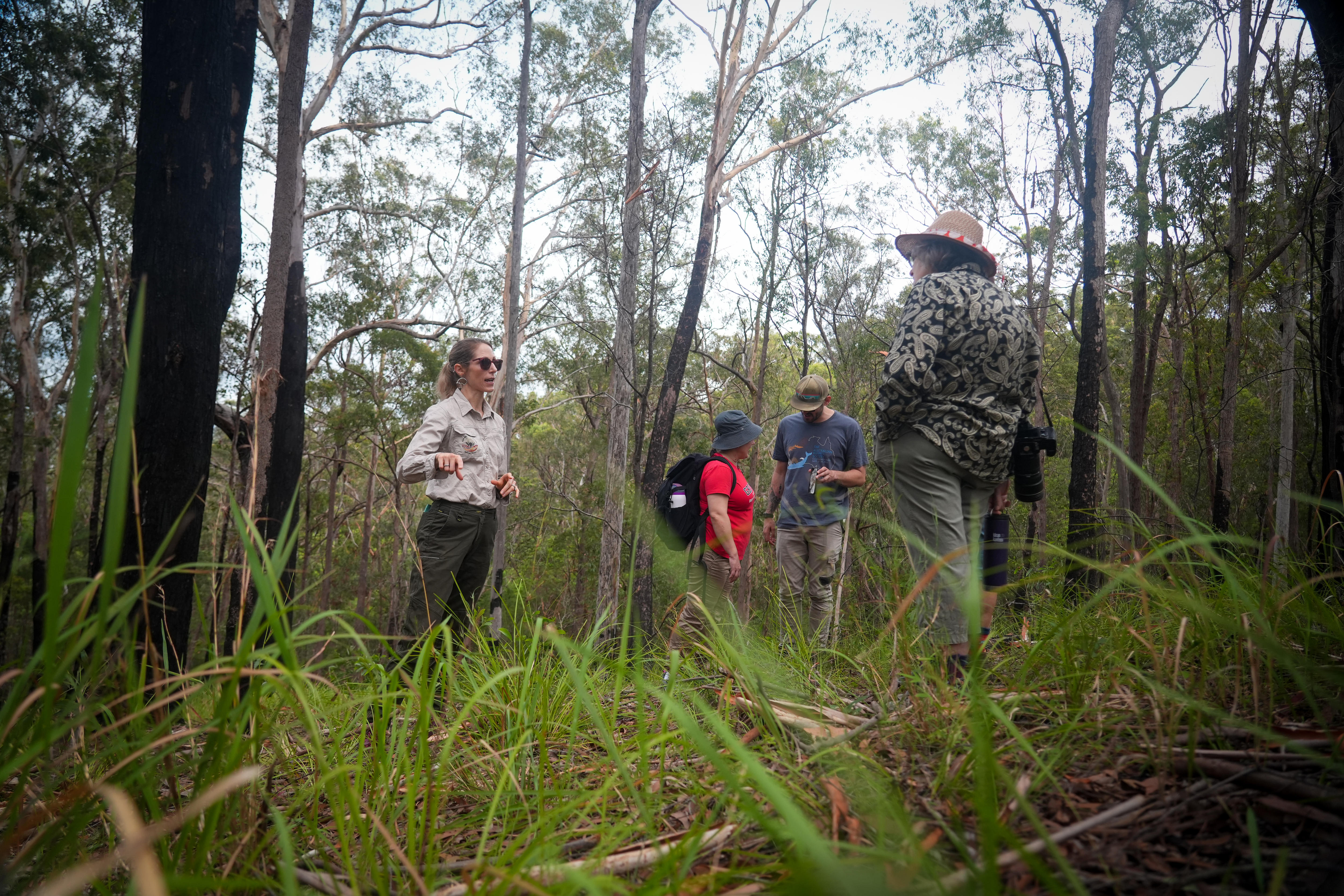 Uma mulher conversa com pessoas nos arbustos.
