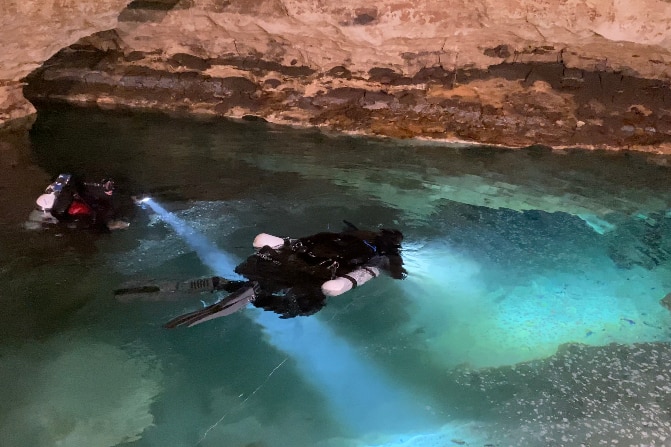 Divers floating on the surface of a cave. 