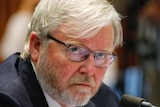 Kevin Rudd sits at a desk with a microphone in front of him