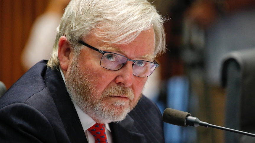 Kevin Rudd sits at a desk with a microphone in front of him