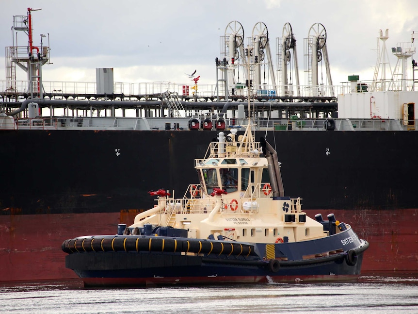 A tug pulls up next to an oil tank in the Port of Melbourne
