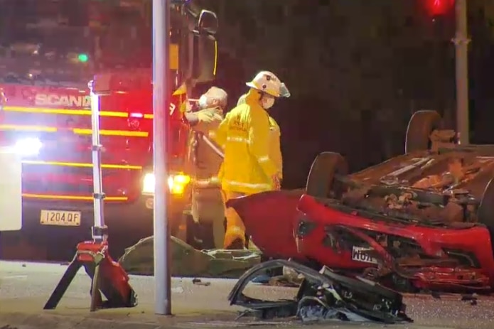 Fire fighters on the scene of an upturned car.