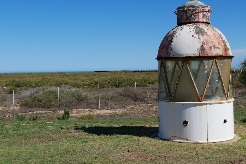 A top of a lighthouse sitting on a grassy area