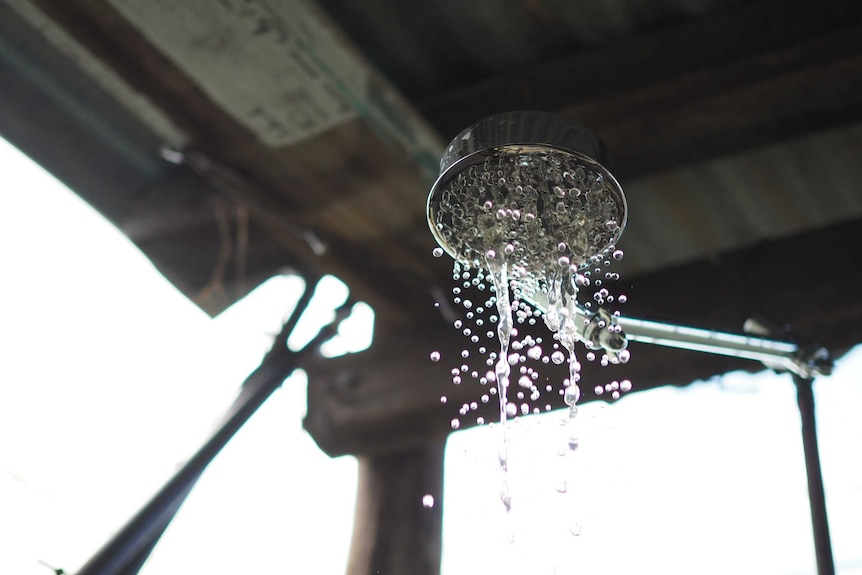 Droplets of water coming out of shower head in outdoor shower cubicle