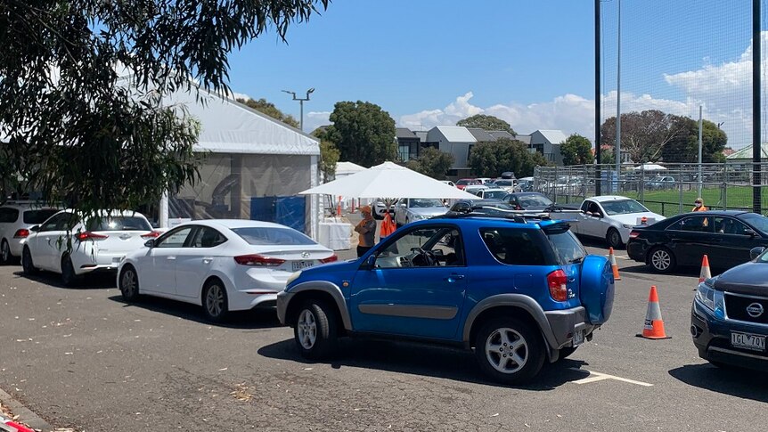 A queue of cars wait outside a tent for coronavirus testing.