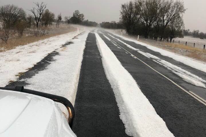Car drives down road with hail blanketing the ground at Condamine in southern Queensland.