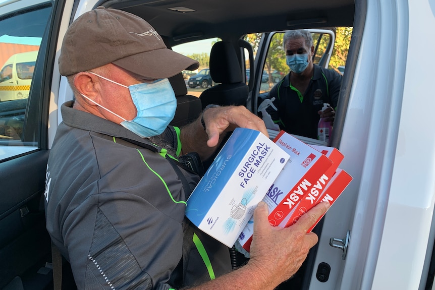 A Larrakia Nation staff member holding boxes of face masks.