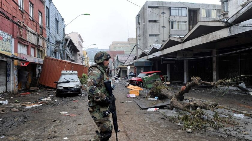 A soldier patrols the debris-covered downtown Talcahuano, Chile