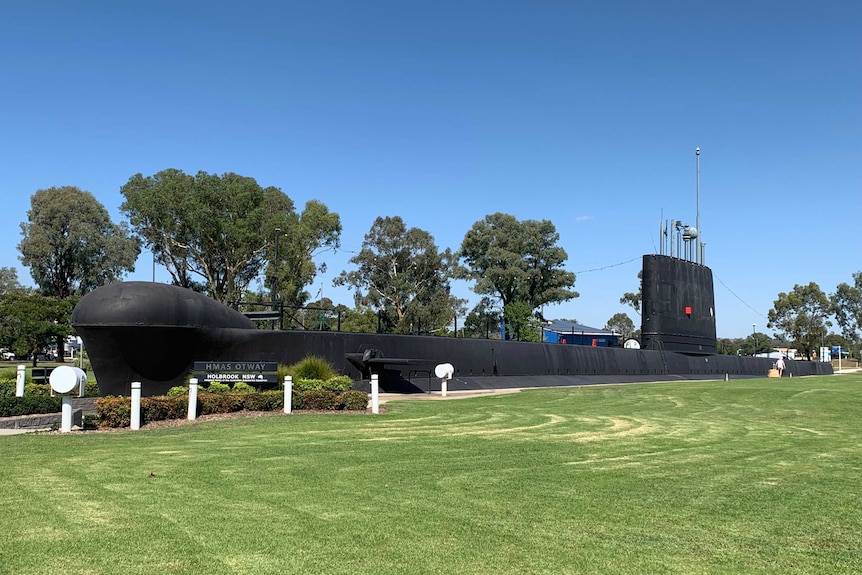 A large black submarine on grass.