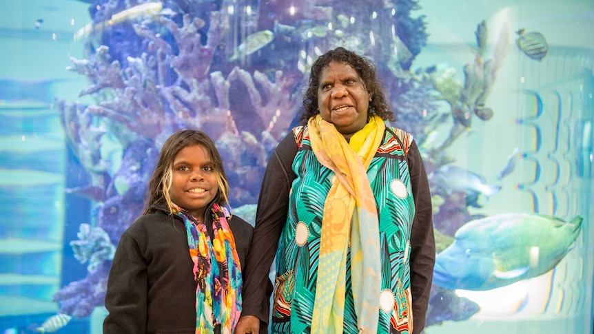 Lily and Zahara stand in front of the hospital's aquarium