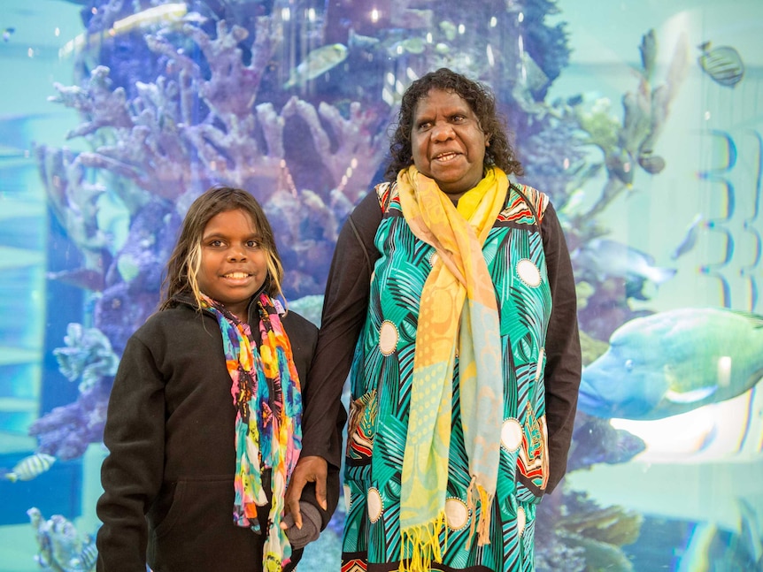 Lily and Zahara stand in front of the hospital's aquarium