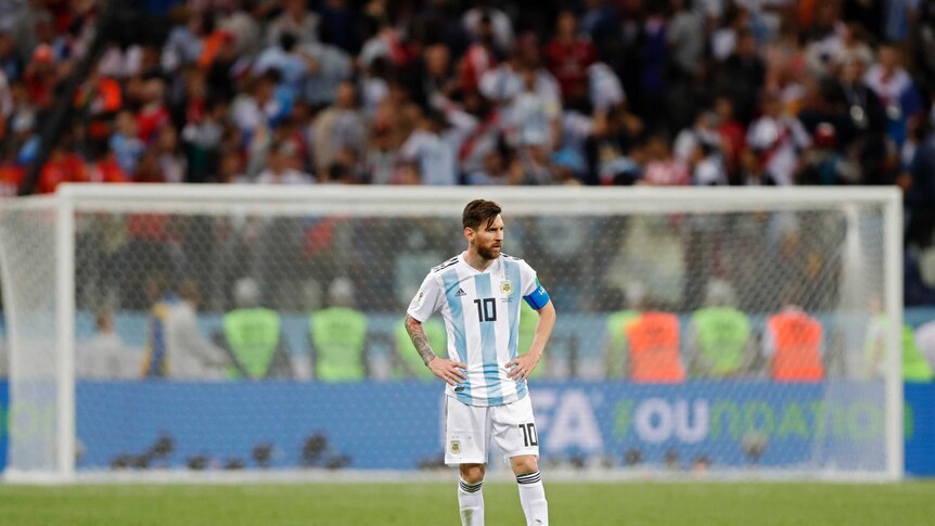 Lionel Messi stands alone with his hands on his hips