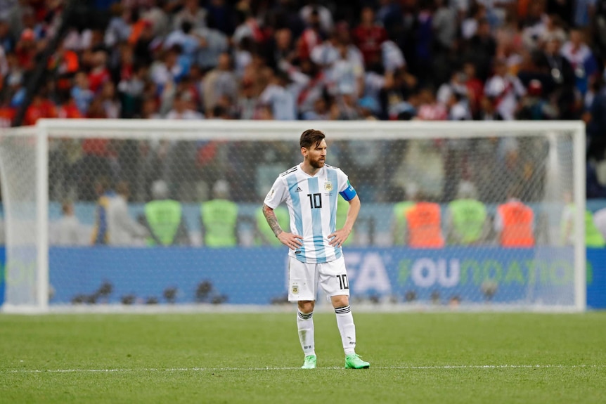 Lionel Messi stands alone with his hands on his hips