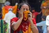 A woman in a sari crying while speaking on the phone