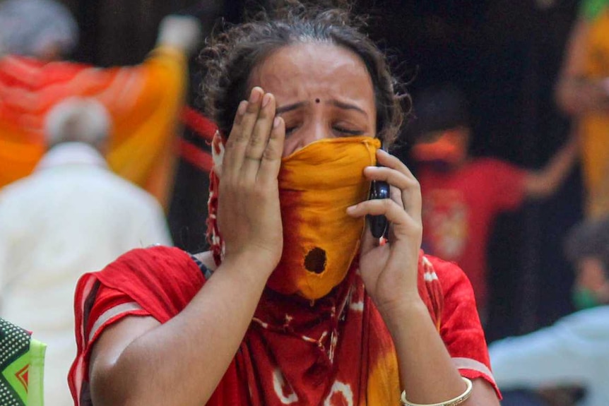 A woman in a sari crying while speaking on the phone