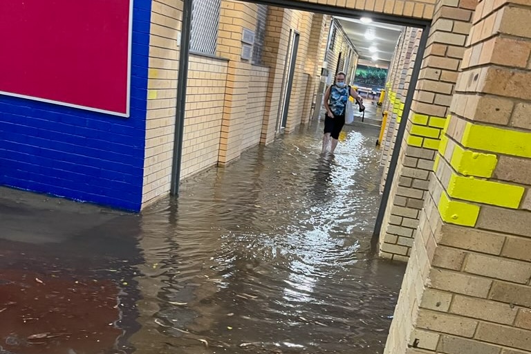 person walks through flood waters in a hallway