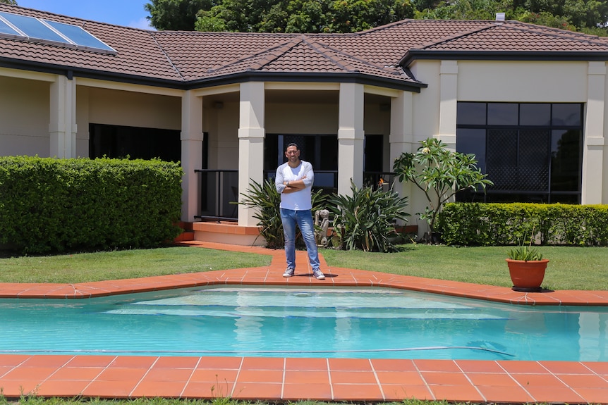 David Nahi standing next to pool in front of house