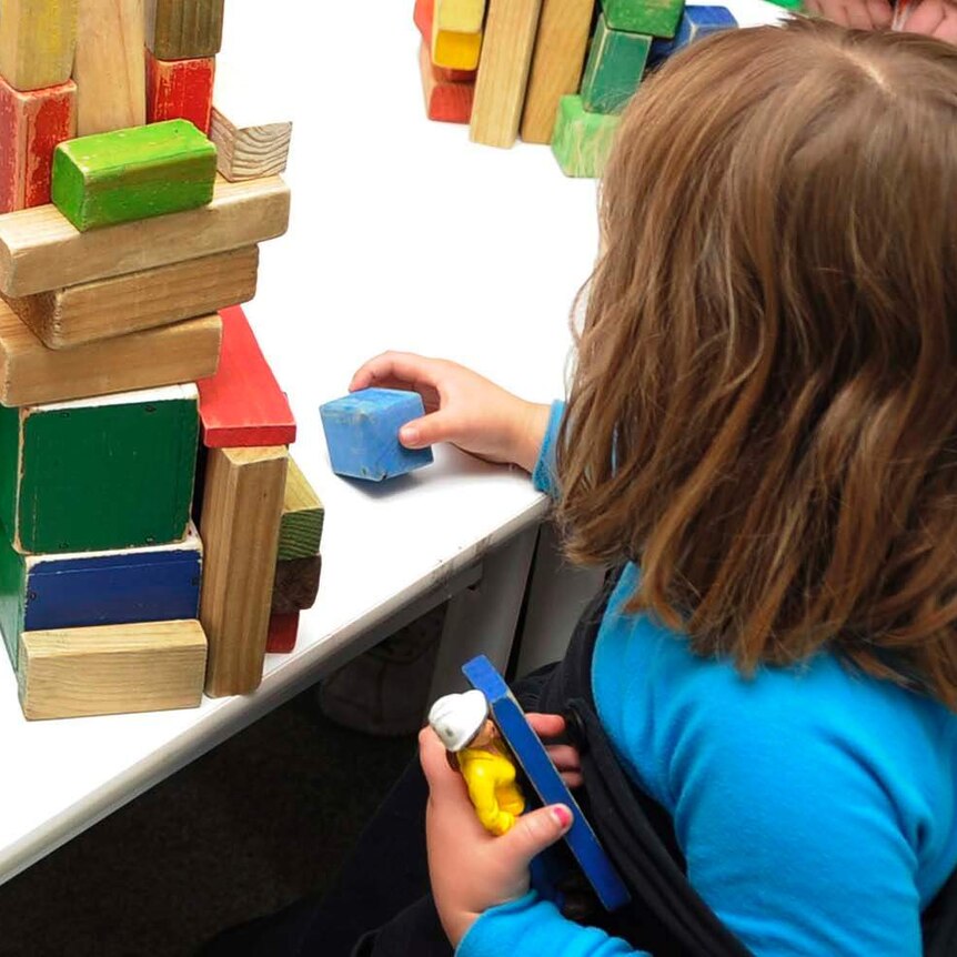 A child plays with coloured blocks at a table