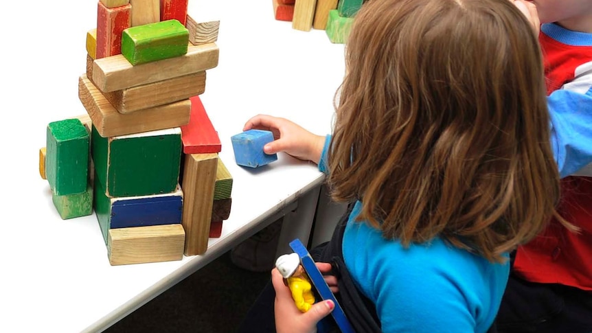A child plays with coloured blocks at a table