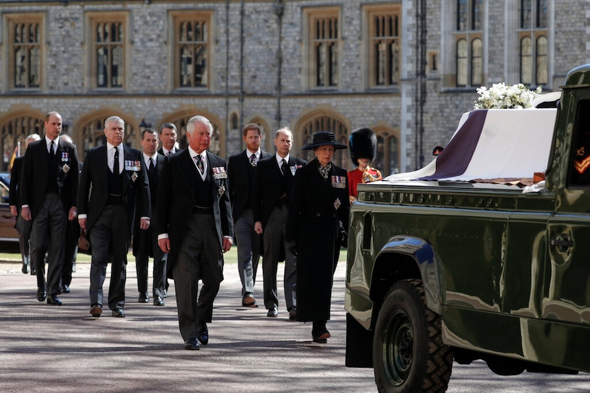 Prince Philip's children and grandchildren walk behind his coffin, draped in a flag and flowers.