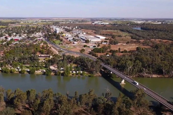 An aerial shot of a township on a river forded by a bridge.
