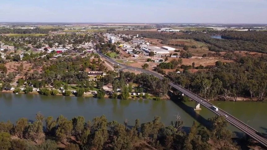 An aerial shot of a township on a river forded by a bridge.