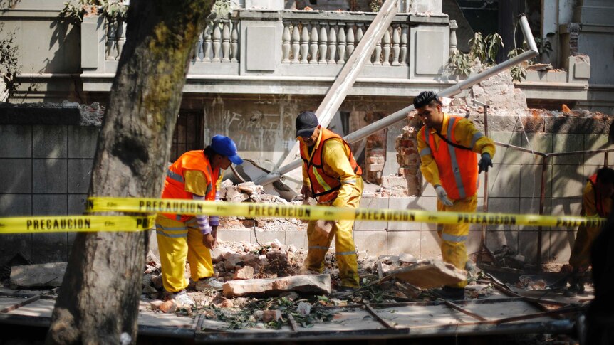 City workers remove the rubble of a wall that collapsed in an earthquake in Mexico City