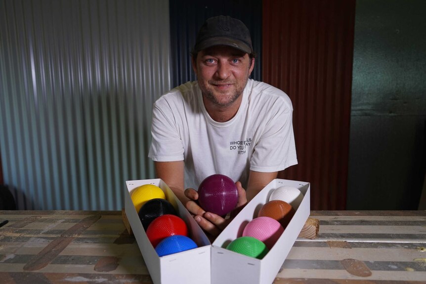 Paul Manwaring stands with his croquet balls, which are each a different colour.