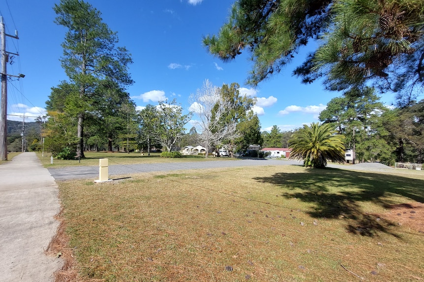 The street view of an old country motel, with a large grassed area in front.