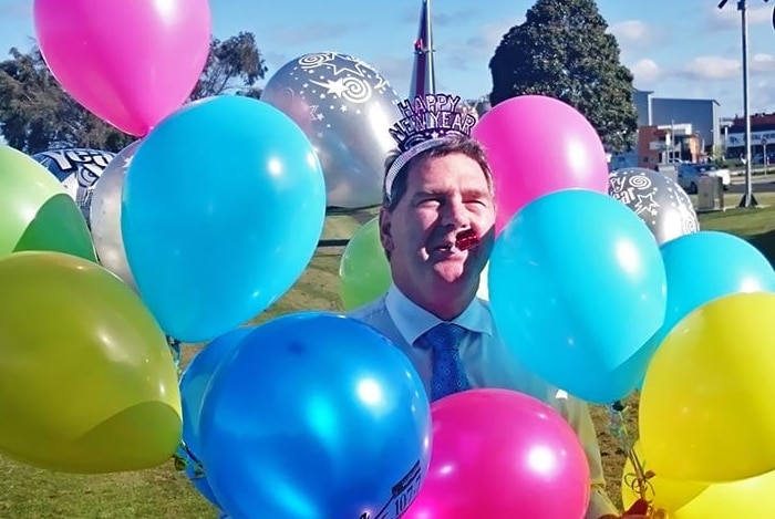 Man with party hat and balloons.