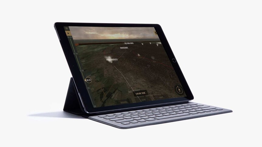 A table device propped up on a keyboard accessory. The screen shows an aerial view of a landscape with labelled landmarks.