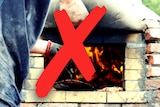 A man stoking an outdoor pizza oven. A big red cross over the graphic means 'no'.