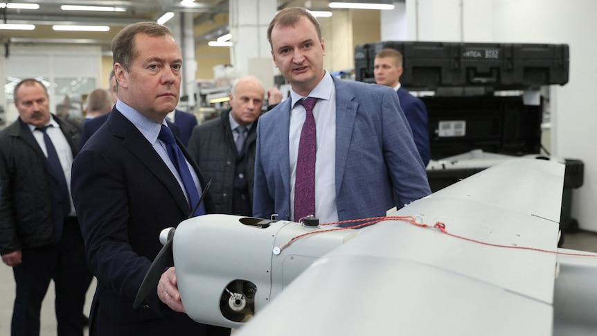 Dmitry Medvedev (left) examines a drone.