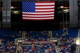 President Donald Trump supporters listen under a large American flag as Trump speaks during a campaign rally